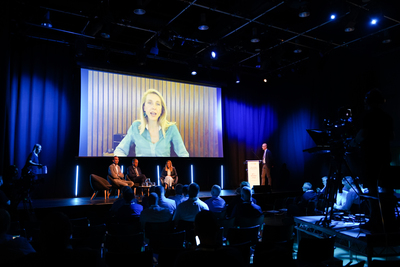 Sibyle Veil, Chief Executive Officer of Radio France on a screen above the stage, addresses the audience at WorldDAB Automotive 2022