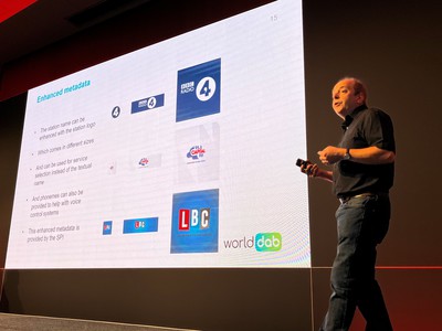 Lindsay Cornell on stage at IBC in front of a slide showing information on metadata and radio station logos