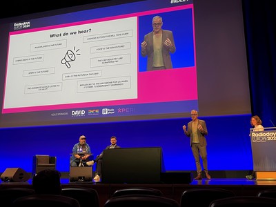 The Playbook session on stage at Radiodays Europe 2024 with two speakers seated, and two standing on stage at the lecturn