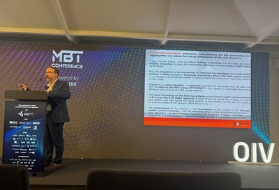 Luis Grela of TRedess on stage at MBT conference behind a lecturn, in front of a slide with text showing that transmitter manufacturers are key contributors to reducing energy consumption