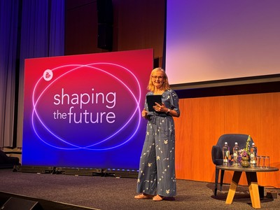 WorldDAB Project Director Bernie ONeill on stage at IBC2025 holding an iPad in front of the IBC logo with the words "shaping the future"